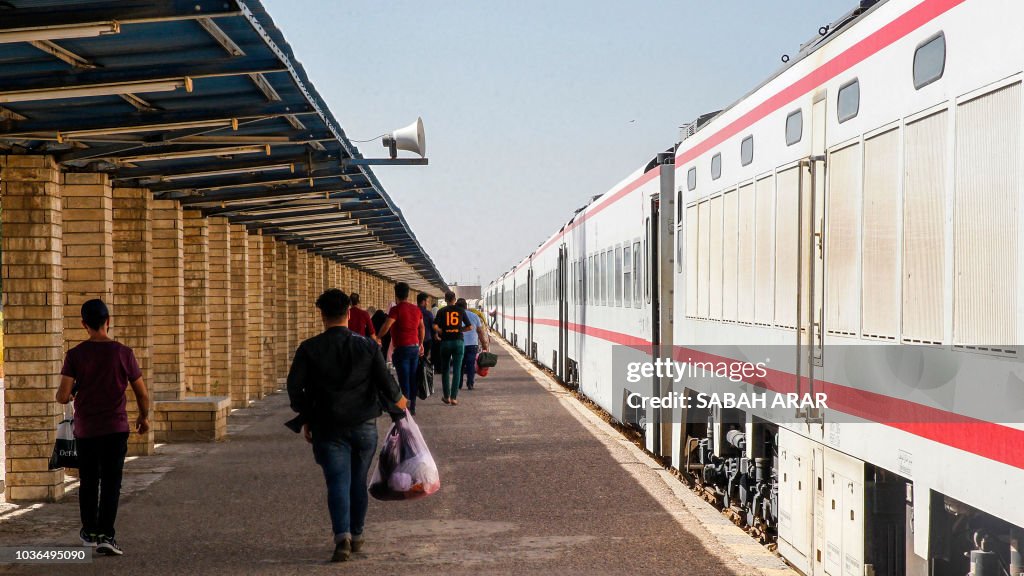 Iraq Train Rote Iraqi passengers walk with luggage and belongings past a train along ...