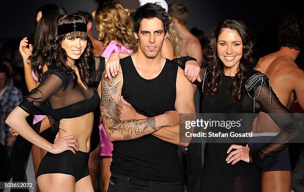 Model poses with Mitchell Johnson and Giaan Rooney on the catwalk during the Hot In The City Intimates group show as part of Rosemount Sydney Fashion...