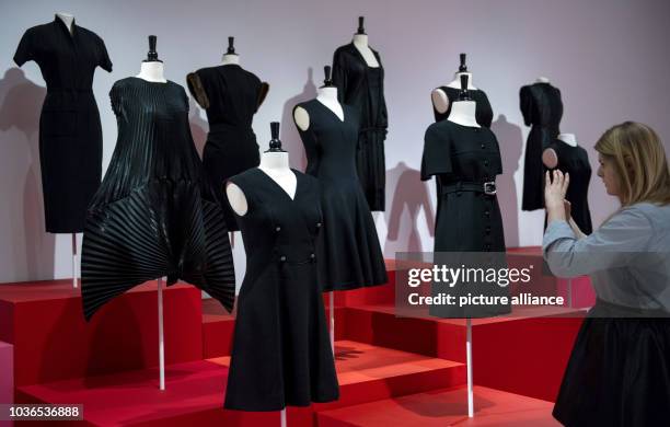 Woman takes pictures of the little black dresses during the exhibition 'Myth Chanel', about the fashion designer Coco Chanel in Hamburg, Germany, 27...