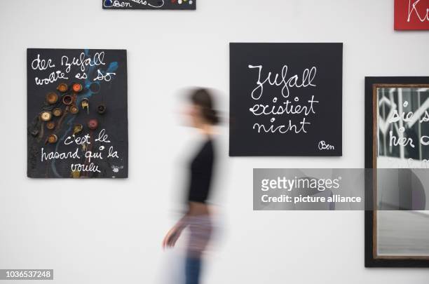 Woman walks past the pieces 'Der Zufall wollte es so - C'est le hasard qui la voulu' from 2005 and '"Zufall existiert nicht' from 2016 by Ben Vautier...