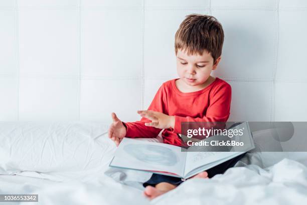 five years old kid reading a book on dad and mom's bed (home interior) - cuento de hadas fotografías e imágenes de stock