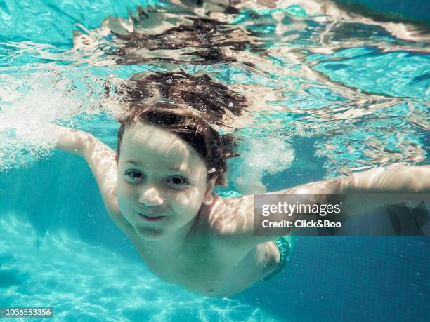 underwater view of a six years old boy in a blue swim suit - six under ストックフォトと画像