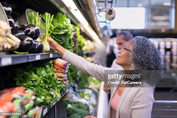 an interracial senior couple goes grocery shopping together - baby boomer stock pictures, royalty-free photos & images