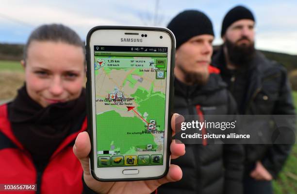 Amateur 'treasure hunters' Franziska Dennstedt , presenting her GPS capable smartphone and co-treasure hunters Sebastian Schwarz and Peter Scharf...