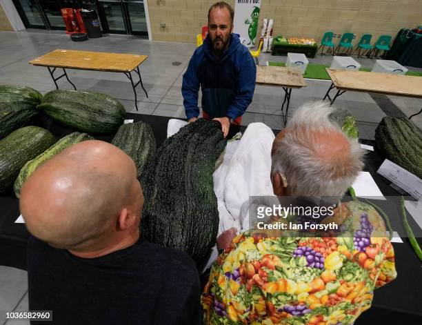 Kevin Fortey and Ian Neale are helped by Chris Marriot to arrange a giant marrow as they arrive overnight for the giant vegetable competition on the...