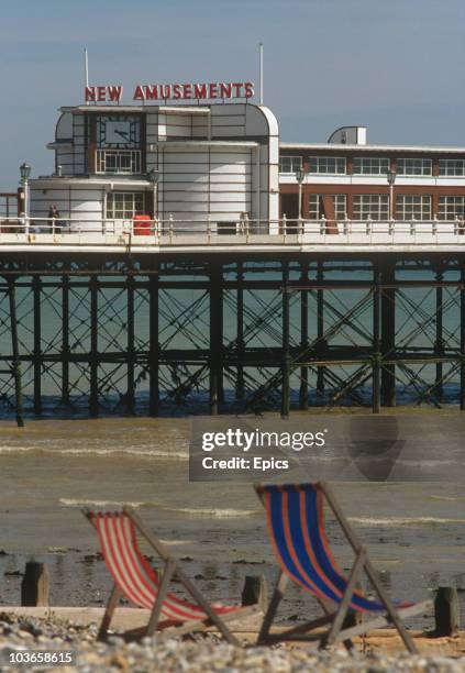 Empty deck chairs wait for occupants in view of the pier in the seaside town of Worthing, West Sussex, circa 1984.