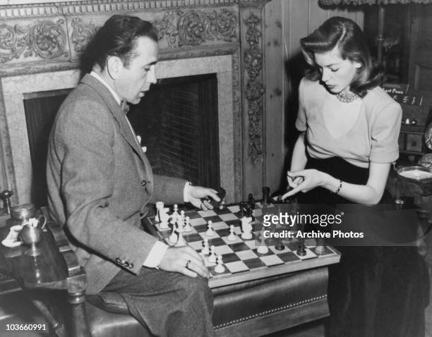 Actor Humphrey Bogart and his wife, actress Lauren Bacall, pictured playing chess, USA, circa 1955.