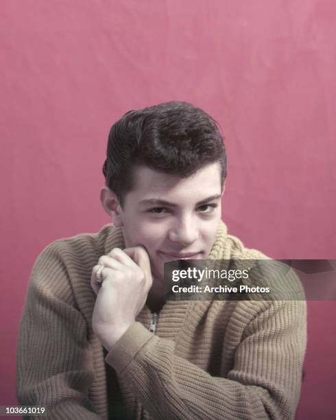 Singer and actor Frankie Avalon pictured smiling in a studio portrait, USA, circa 1955. Avalon is wearing a beige knitted cardigan.