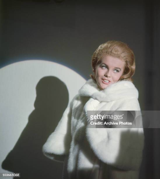 Actress Ann-Margret pictured in a studio portrait, USA, circa 1965. Ann-Margret Olsson wears white fur coat, with her silhouette cast on the wall...