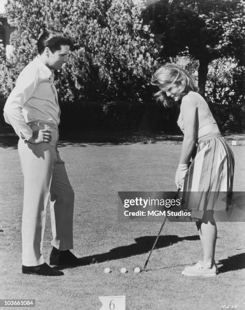 Singer Elvis Presley and actress Ann-Margret put in some putting practice in a scene from 'Viva Las Vegas', USA, circa 1956.