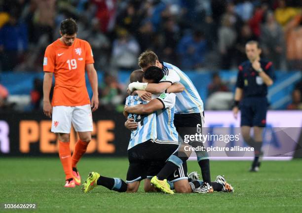 Argentina's Javier Mascherano celebrates with his teammates next to Klaas-Jan Huntelaar of Netherlands after winning the penalty shoot-out of the...