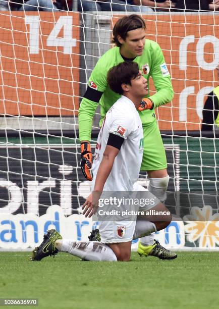 Augsburg's goalkeeper Marwin Hitz comforts teammate Jeong-Ho Hong after the latter caused a penalty kick during the German Bundesliga soccer match...