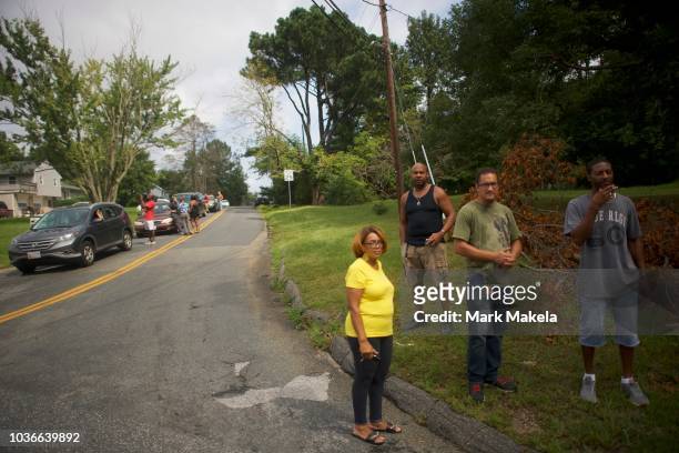 Locals gather across the street from a barricade near the business park where multiple people were killed and injured in a shooting on September 20,...
