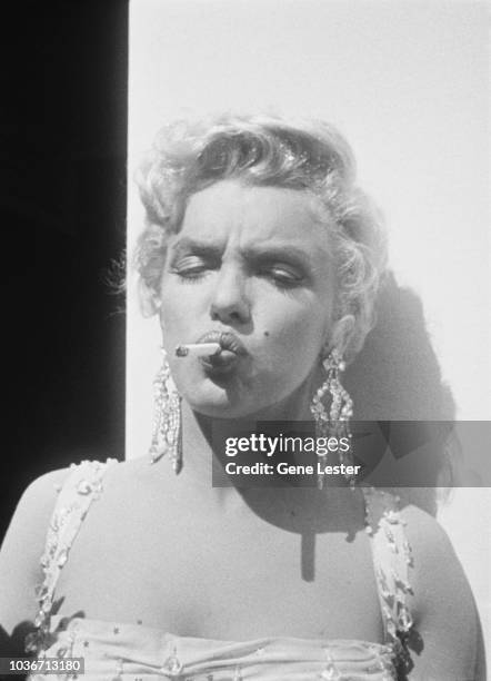 American actress Marilyn Monroe smokes a cigarette on the set of 'There's No Business Like Show Business', directed by Walter Lang, at the 20th...