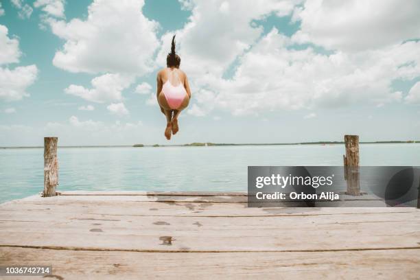 frau springt vom pier - jumping into water stock-fotos und bilder