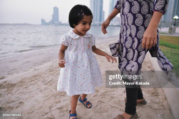 young girl (2-3 years) with mother at the beach sand - arab mom stock-fotos und bilder