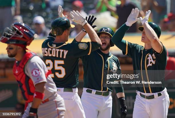 Stephen Piscotty of the Oakland Athletics is congratulated by Jed Lowrie and Matt Chapman after Piscotty hit a three-run home run against the Los...