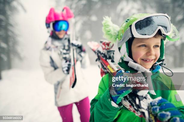 little skiers carrying skis on a winter day - family winter sport stock pictures, royalty-free photos & images