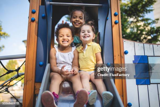 lovely mixed race siblings playing on a playground - toddlers playing outdoor stock pictures, royalty-free photos & images