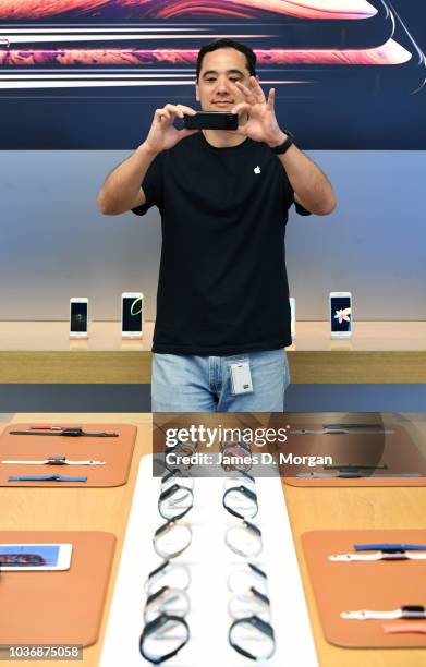 An Apple staff member photographs the new Apple watch models at the Australian release of the latest iPhone and watch models at the Apple Store on...