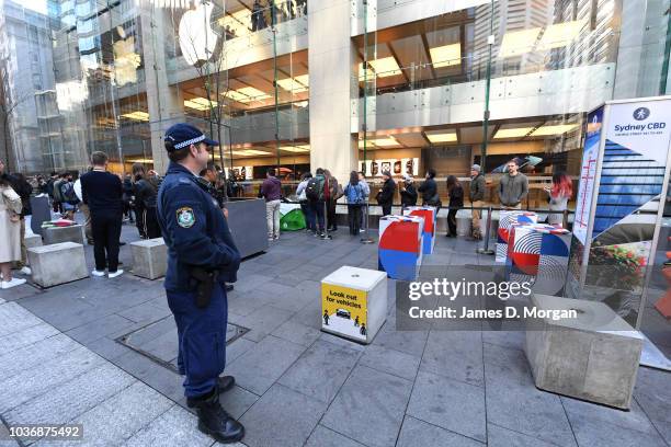 Police office watches customers line up at the Australian release of the latest iPhone models at the Apple Store on September 21, 2018 in Sydney,...