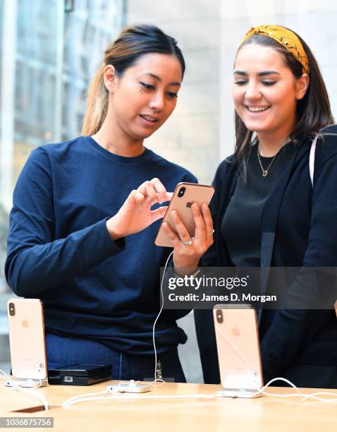 An Apple staff member shows a customer the new phone at the Australian release of the latest iPhone models at the Apple Store on September 21, 2018...