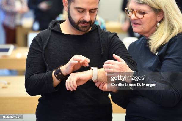 An Apple staff member shows the new watch to a customer at the Australian release of the latest iPhone and watch models at the Apple Store on...