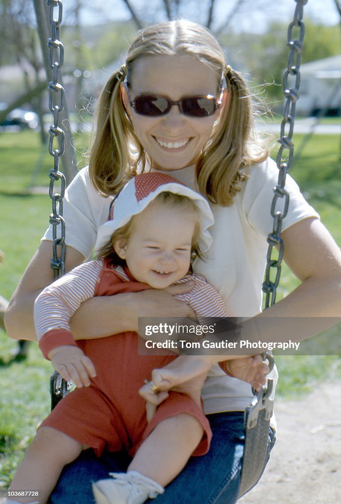 Mother and infant daughter swinging and tickling