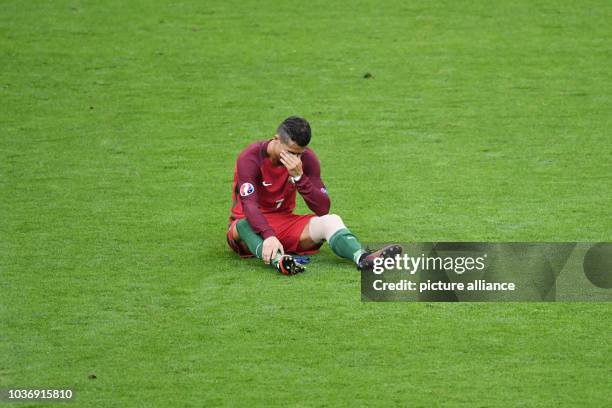 Cristiano Ronaldo of Portugal sits injured on the pitch during the UEFA EURO 2016 soccer Final match between Portugal and France at the Stade de...