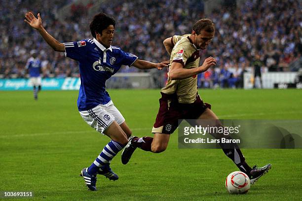 Atsuto Uchida of Schalke challenges Konstantin Rausch of Hannover during the Bundesliga match between FC Schalke 04 and Hannover 96 at Veltins Arena...