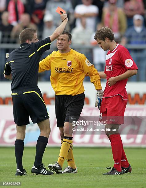 Referee Martin Thomsen presents the red card to Florian Hoernig of Regensburg during the Third League match between SSV Jahn Regensburg v Eintracht...