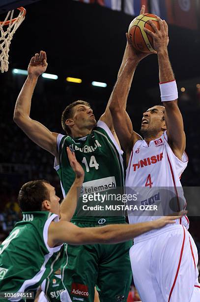 Radhouane Slimane of Tunisia takes a rebound as Gasper Vidmar of Slovenia tries to stop him during the preliminary round group B match between their...