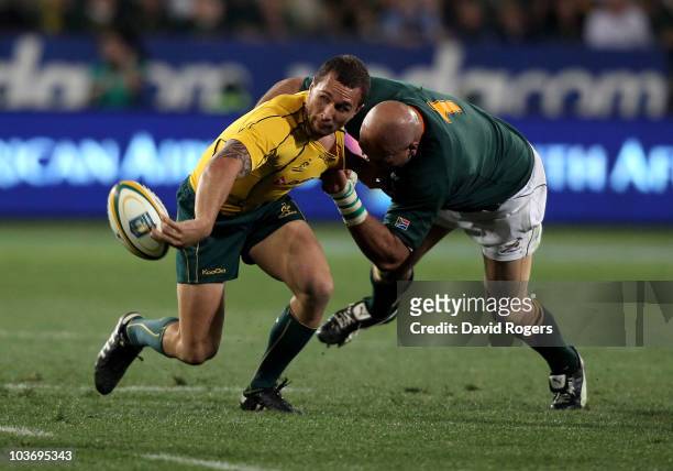 Quade Cooper of the Wallabies off loads the ball as Gurthro Steenkamp tackles during the 2010 Tri-Nations match between the South African Springboks...