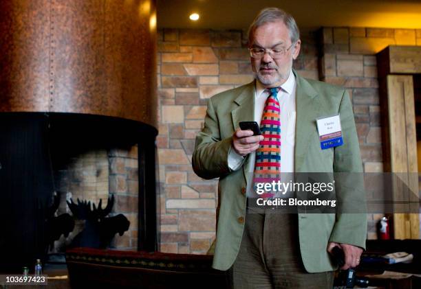 Charles Bean, deputy governor of the Bank of England, checks his mobile phone during the Federal Reserve Bank of Kansas City annual symposium near...