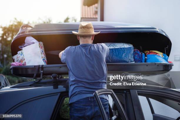 man loading a car roof box with luggage before vacation - car roof box stock-fotos und bilder