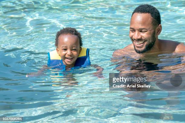 father in swimming pool with toddler - babyschwimmen stock-fotos und bilder