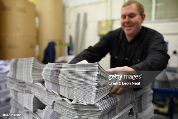 Member of the packing team stacks copies of the weekly newspaper as the latest edition is printed at the Barnsley Chronicle press during a nightshift...