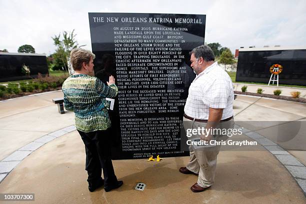 Two people pay tribute at marble wall honoring those who died or suffered at a memorial park to victims of Hurricane Katrina on August 29, 2010 in...