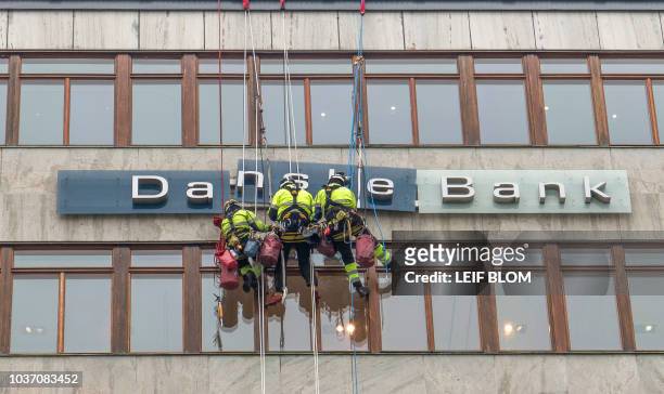 Picture taken on April 7, 2016 shows workers maintaining the "Danske Banks" sign in central Stockholm, Sweden. - Denmark's financial watchdog on...