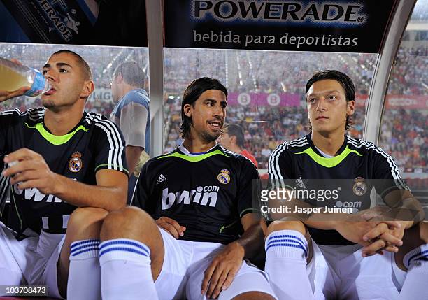 Sami Khedira of Real Madrid sits on the bench flanked by his teammates Mesut Ozil and Karim Benzema during the La Liga match between Mallorca and...
