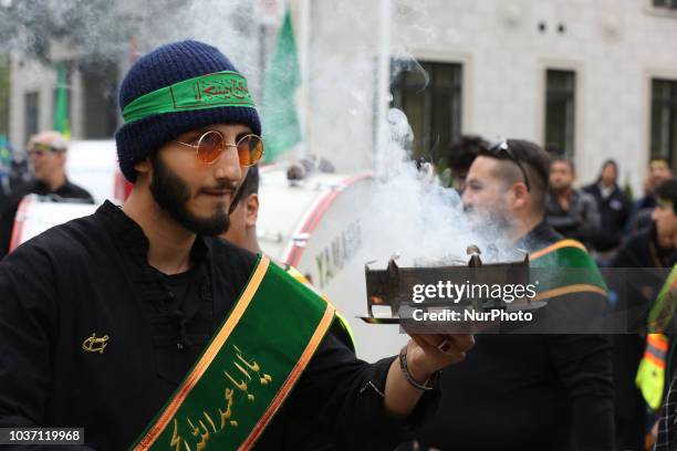 Man hold incense to bless participants as Shiite Muslim mourners take part in a Muharram procession in Toronto, Ontario, Canada, on September 20,...