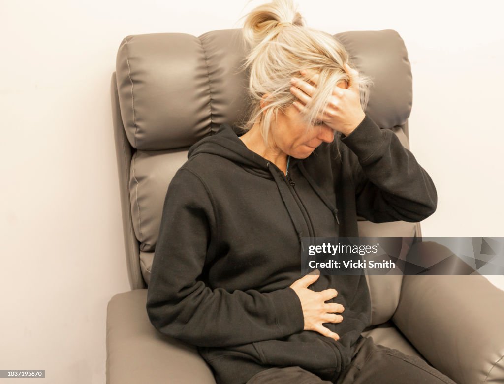 Woman sitting in a chair clutching stomach
