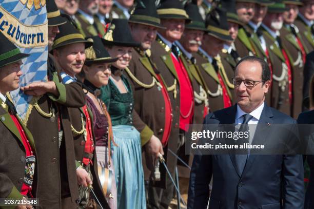 French President Francois Hollande walks past the Gebirgsschuetzen, the traditional Bavarian militia, after arriving at the airport in Munich,...