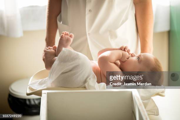 doctor measuring baby on weight scale - cute nurses fotografías e imágenes de stock