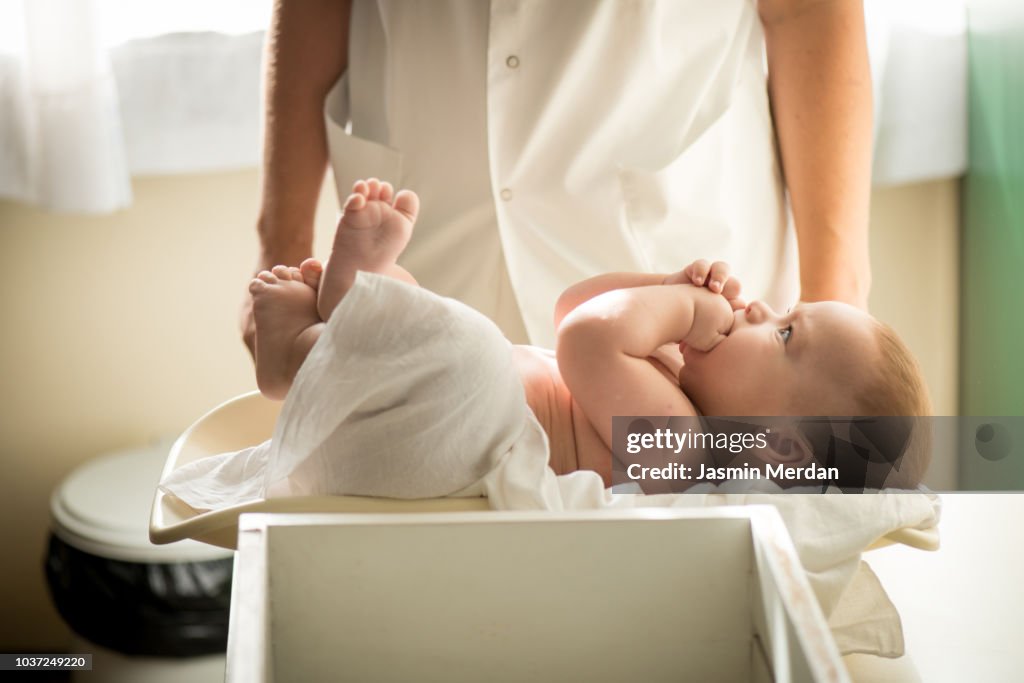 Doctor measuring baby on weight scale