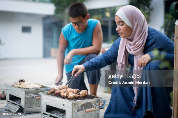 boy and girl working on barbecue grill - hot arabic girl stock pictures, royalty-free photos & images