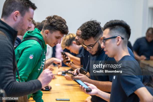 Employees assist customers with Apple Inc. Products during a sales launch at an Apple Inc. Store in New York, U.S., on Friday, Sep. 21, 2018. The...