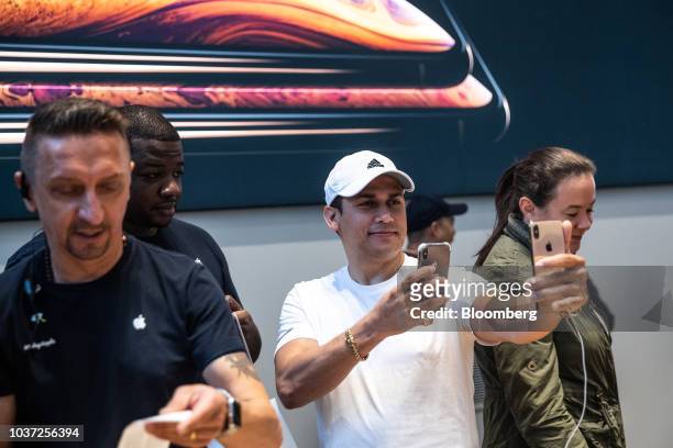 Customer uses a mobile device to take a photograph of the Apple Inc. IPhone XS smartphone during a sales launch at a store in New York, U.S., on...