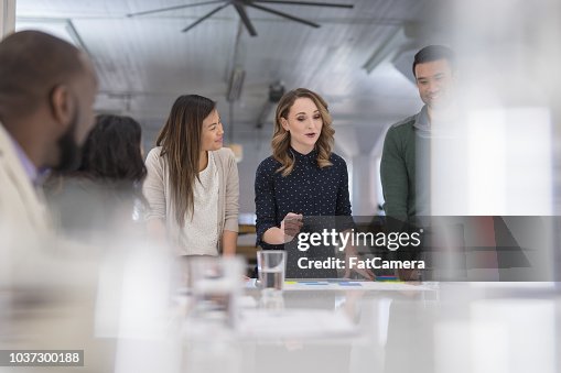 A mixed-ethnic group of business colleagues sign paperwork at the conference table A mixed-ethnic group of business colleagues sign paperwork at the conference table