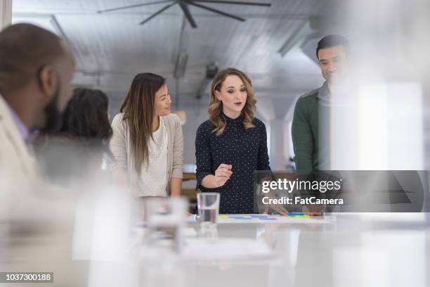 a mixed-ethnic group of business colleagues sign paperwork at the conference table - global solutions stock pictures, royalty-free photos & images